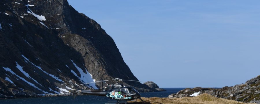 Helicopter on snowy mountain by the sea, showcasing Helipaddy landing locations.