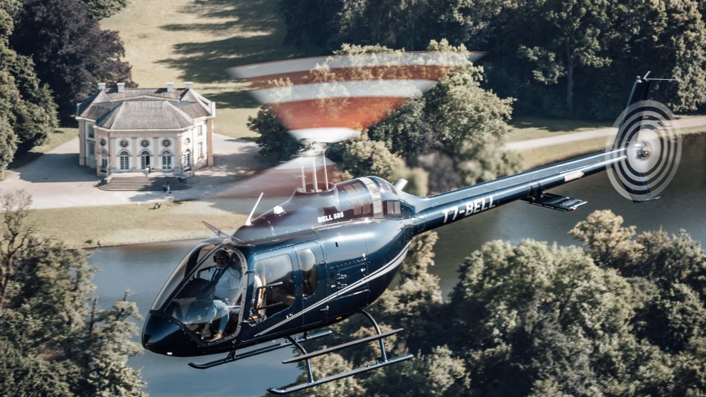 Helicopter flying over scenic estate, showcasing Helipaddy's luxury travel experience.