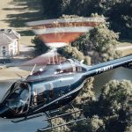 Helicopter flying over scenic estate, showcasing Helipaddy's luxury travel experience.