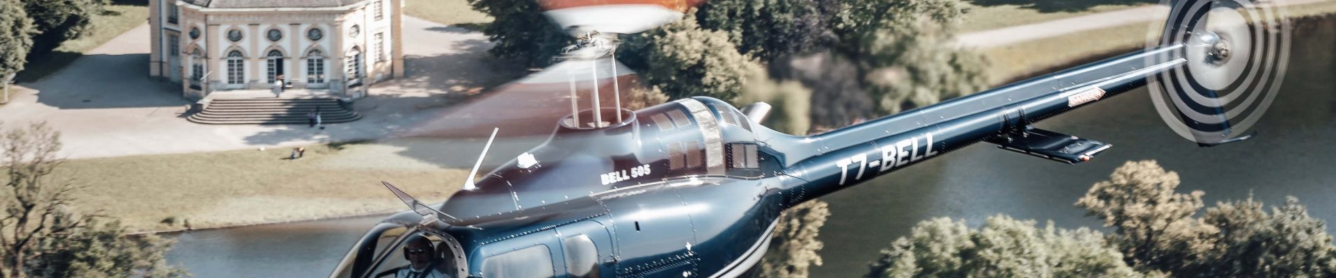 Helicopter flying over scenic estate, showcasing Helipaddy's luxury travel experience.