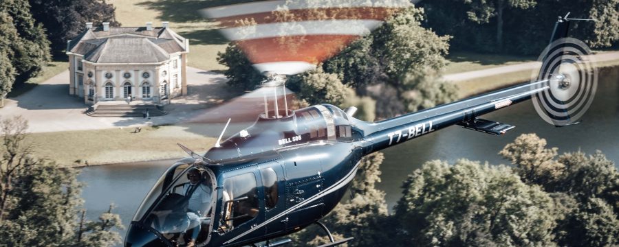 Helicopter flying over scenic estate, showcasing Helipaddy's luxury travel experience.