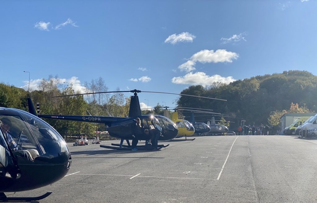 Helipaddy helicopter parking lot with several helicopters lined up on a sunny day.