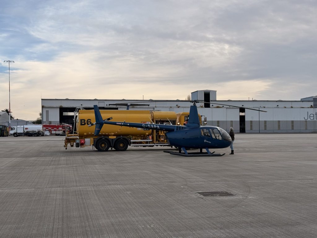 Blue helicopter on tarmac near a fuel truck at an airfield; featured on Helipaddy for aviation enthusiasts.