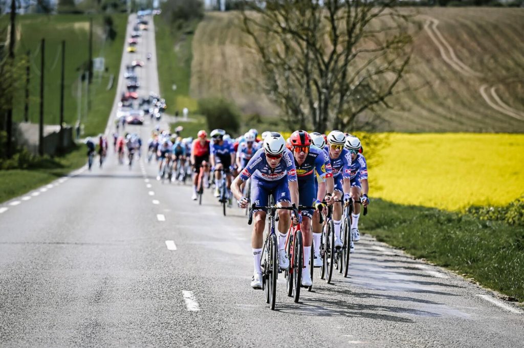 Cyclists race on a scenic rural road, showing dynamic movement and teamwork.